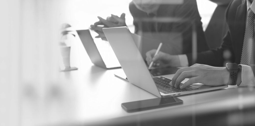 zwei Menschen sitzen nebeneinander jeweils an einem Laptop